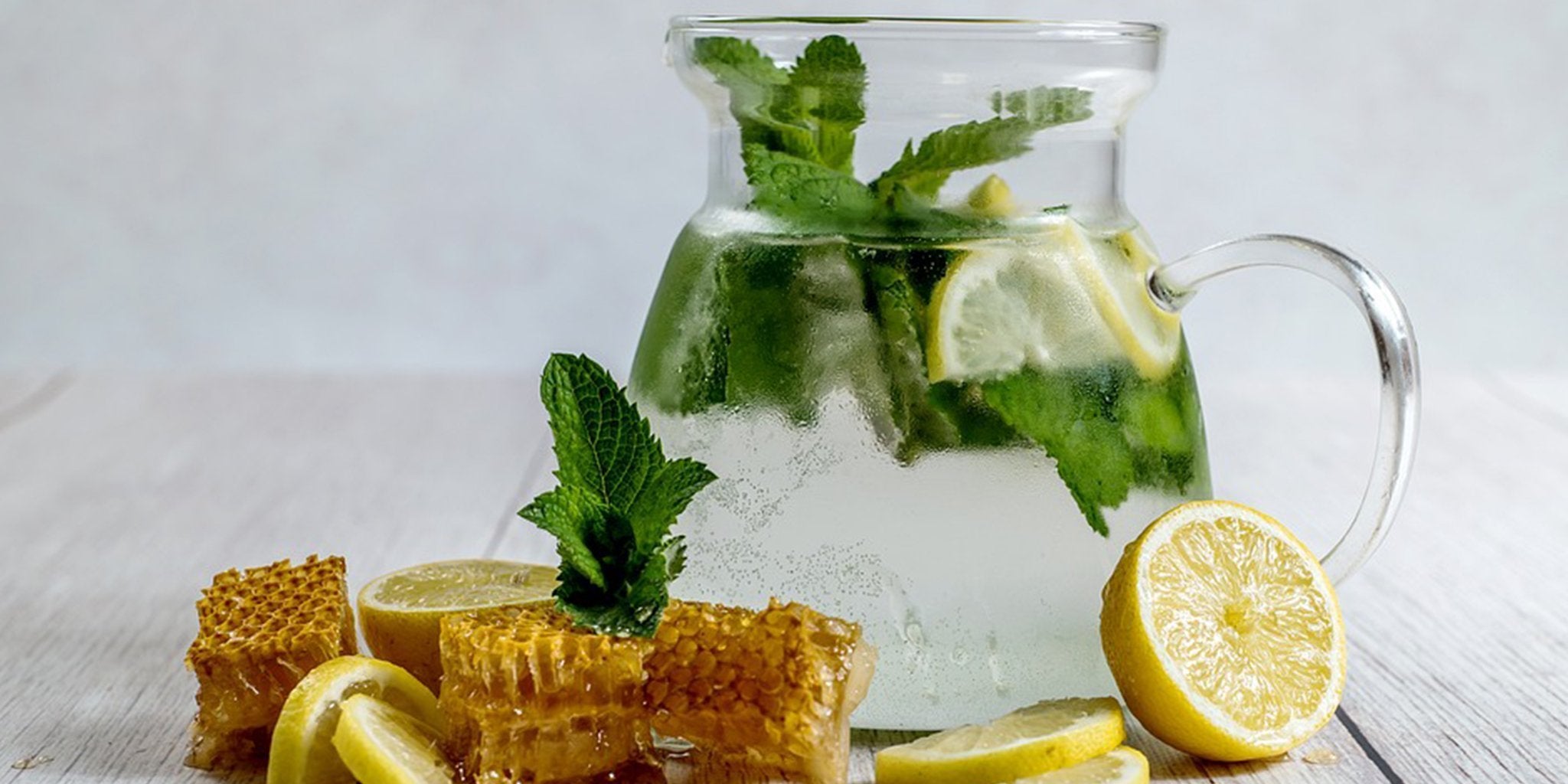 Detoxifying foods including artichokes, kale, basil, lemon, and fennel on wooden table