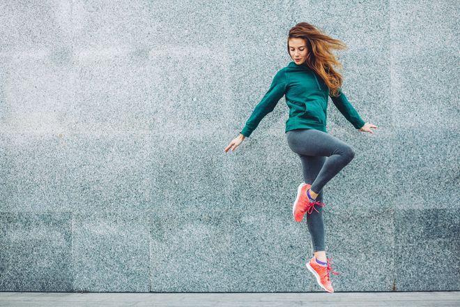 Woman wearing vibrant print leggings doing yoga outside in bright sunlight