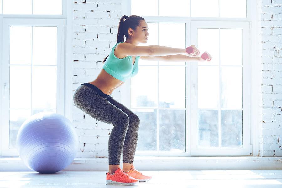 Woman lifting barbell wearing vibrant print leggings in a gym
