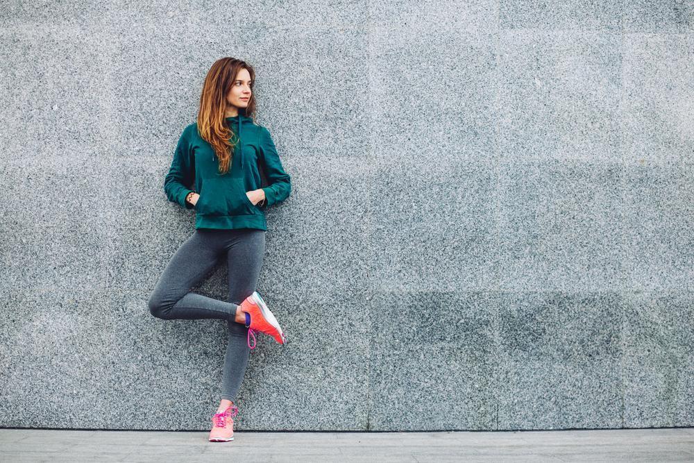 Woman in patterned leggings and denim jacket walks down city street